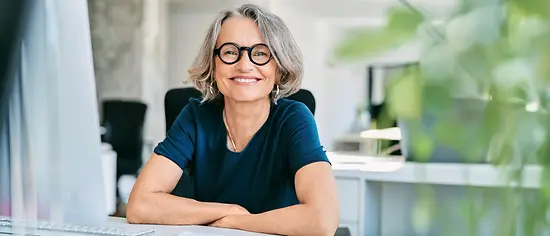 Ältere Dame sitzt und lacht - PlusVorsorge