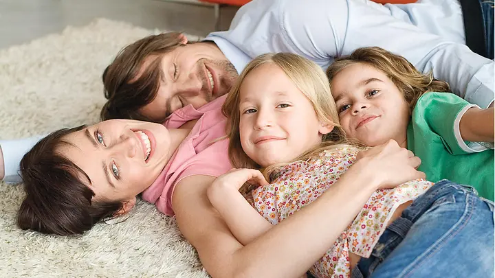 Familie kuschelt auf dem Teppich - Riester Rente