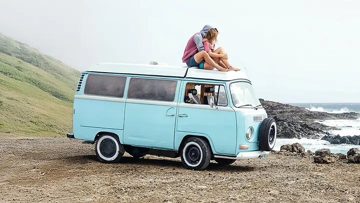 Paar sitzt gemeinsam auf dem Auto - KFZ Versicherung