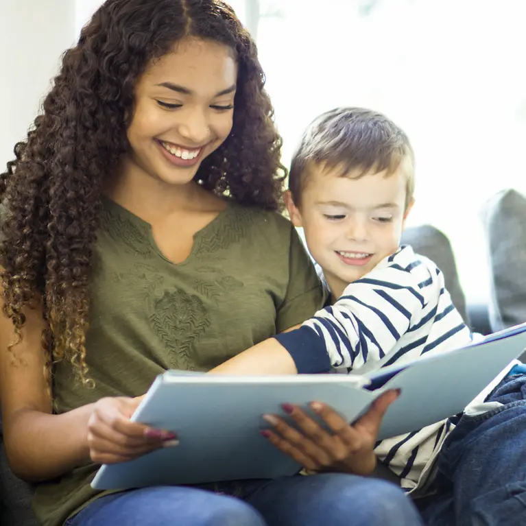 Junge Frau mit Kind liest im Buch - Reiseversicherung Au pairs