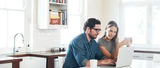 Mann und Frau schauen auf Laptop - Vergleich PKV und GKV