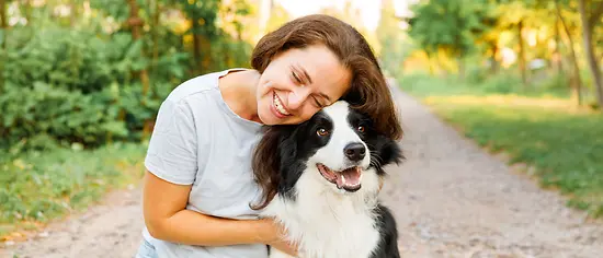 Lächelnde Frau mit Border Collie - Hunde-OP-Versicherung